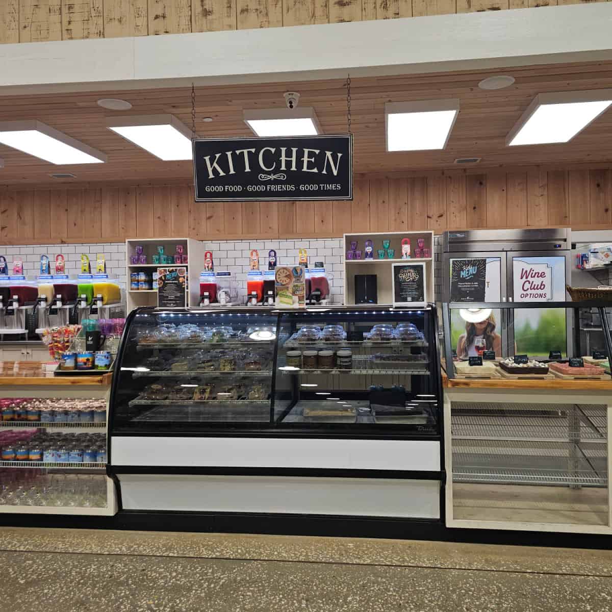 Kitchen sign over a refrigerated case with cheesecakes, fudge on display and sweet treats.