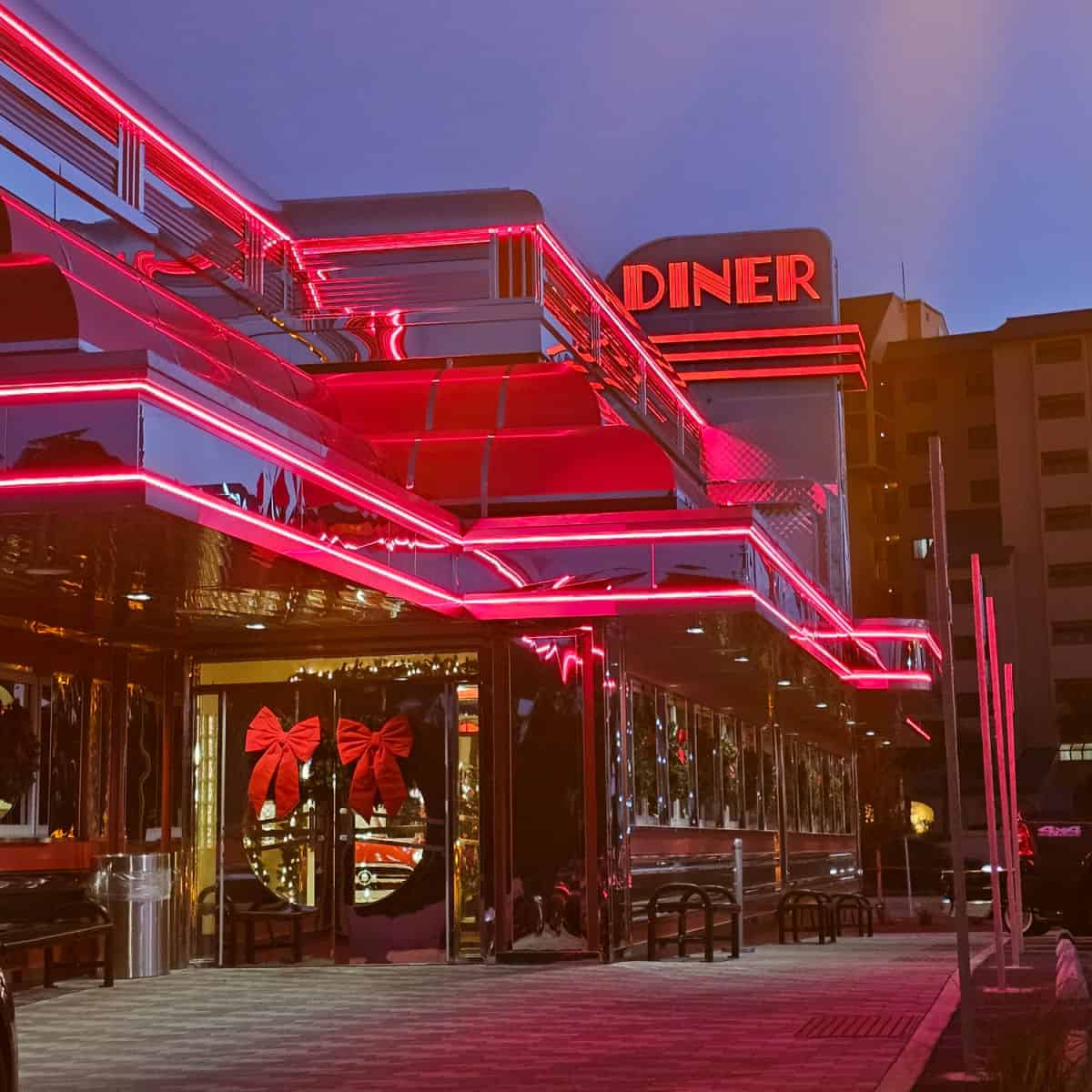 Sunliner Diner exterior at night with red neon lights and diner sign lit up.