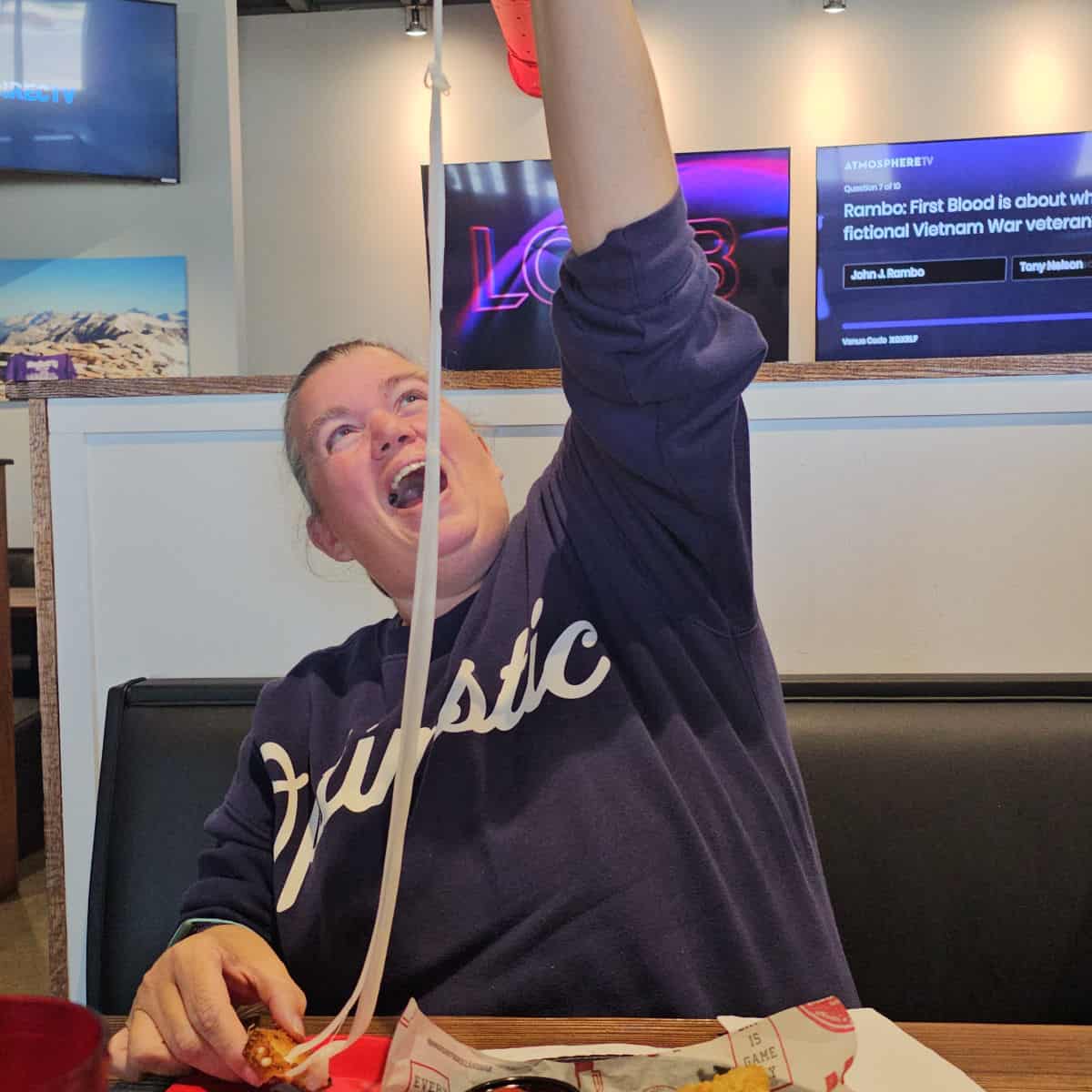 Tammilee laughing while pulling a mozzarella cheese pull from fried cheese