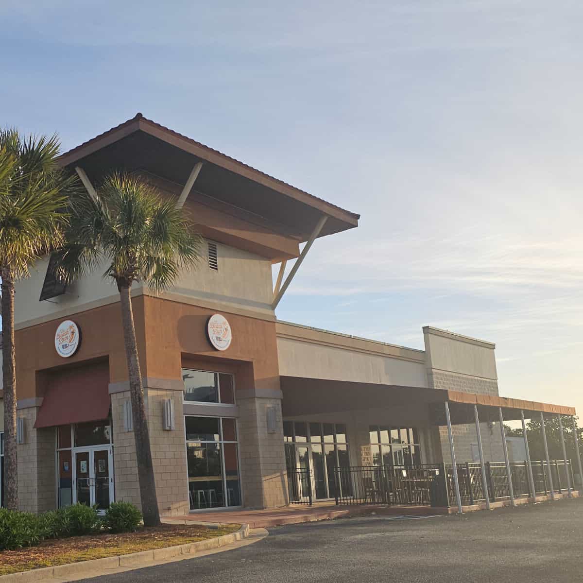 The Beach Bun with covered outdoor seating, two signs on the side of the building