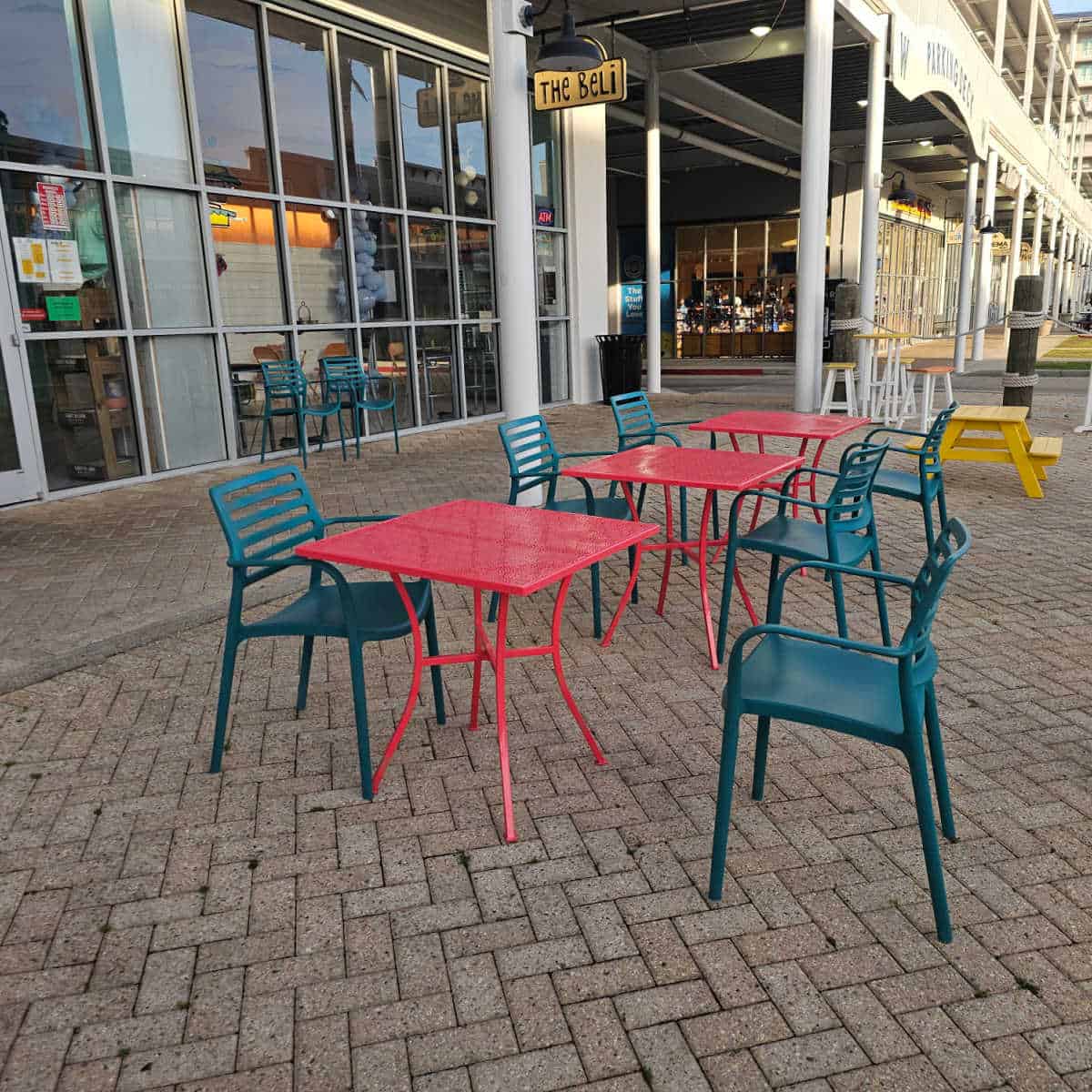 Colorful outdoor tables and chairs in front of The Beli sign at The Wharf