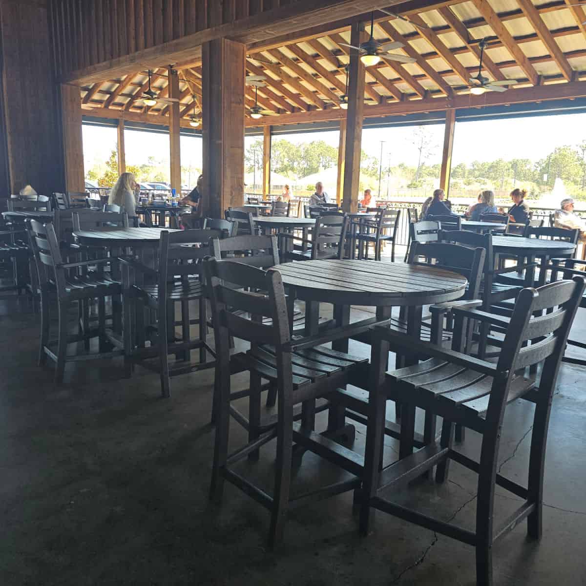 Outdoor patio seating wtih tall chairs and tables, people sitting around with glasses of wine at Duplin Winery