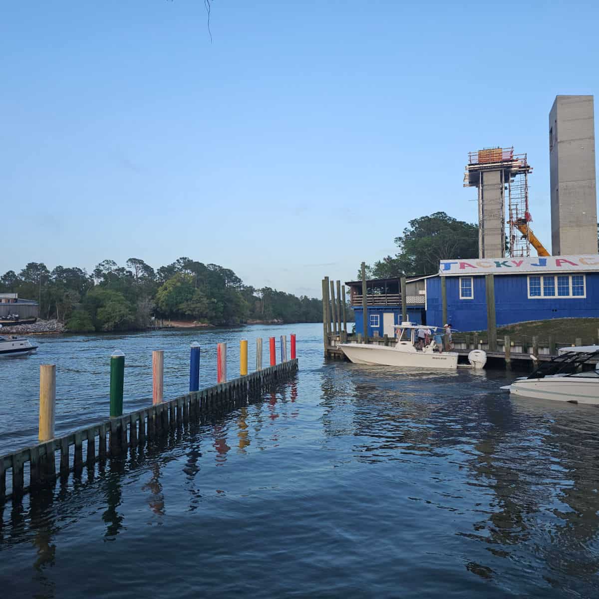 Tacky jacks building with boats on the water and contstruction of the new Gulf Shores pedestrian bridge above it