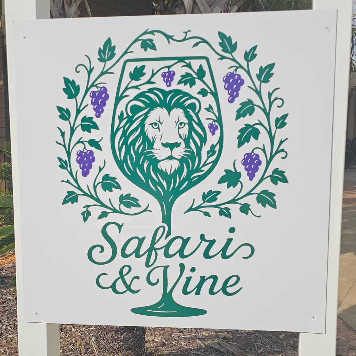 Safari and Vine sign with lion head in a wine glass with vines around it