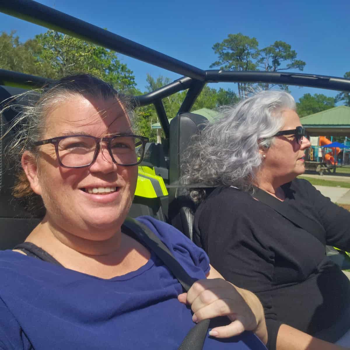 Tammilee and Brandy in a Slingshot with the top off cruising by a playground