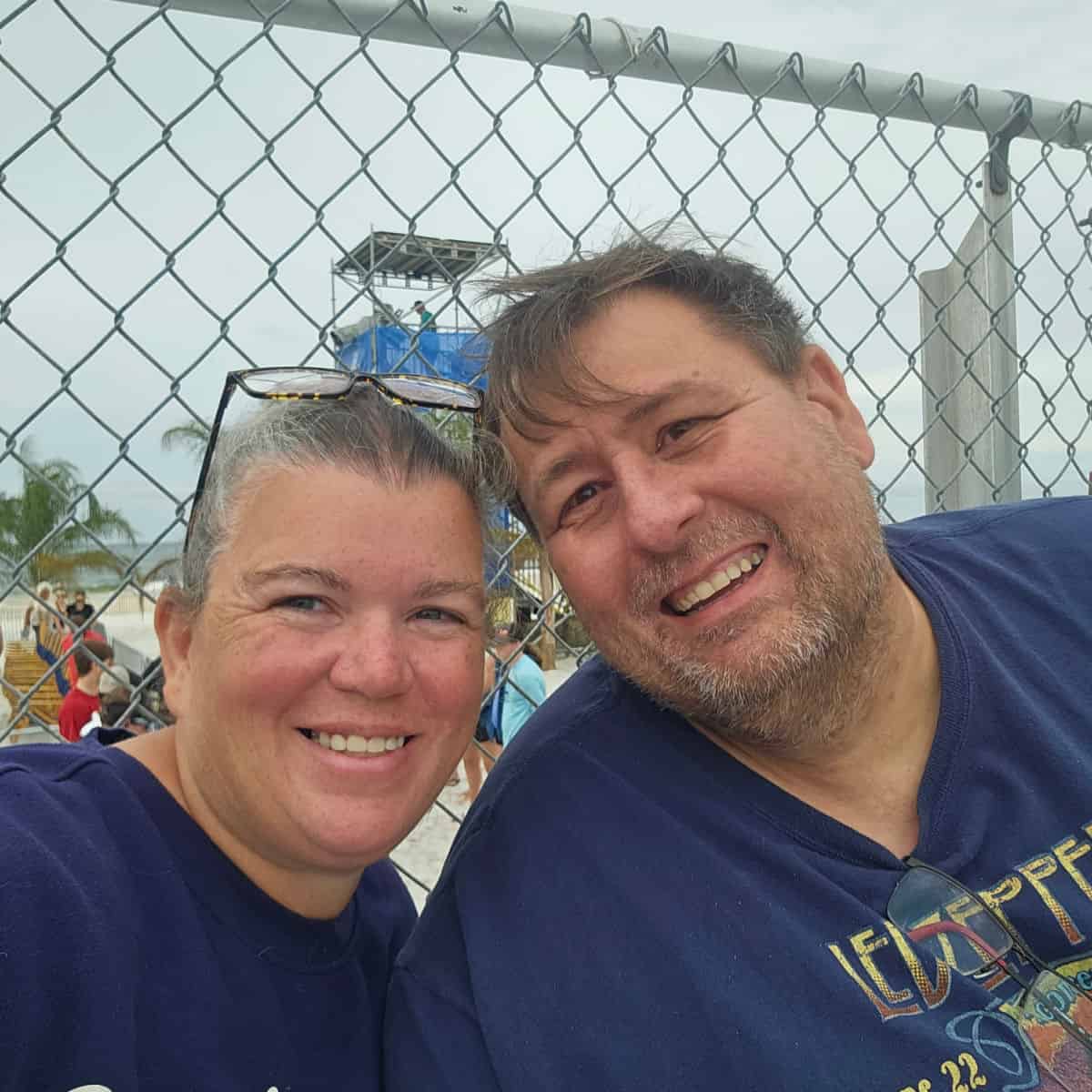 Tammilee and John next to a fence with camera stand behind them