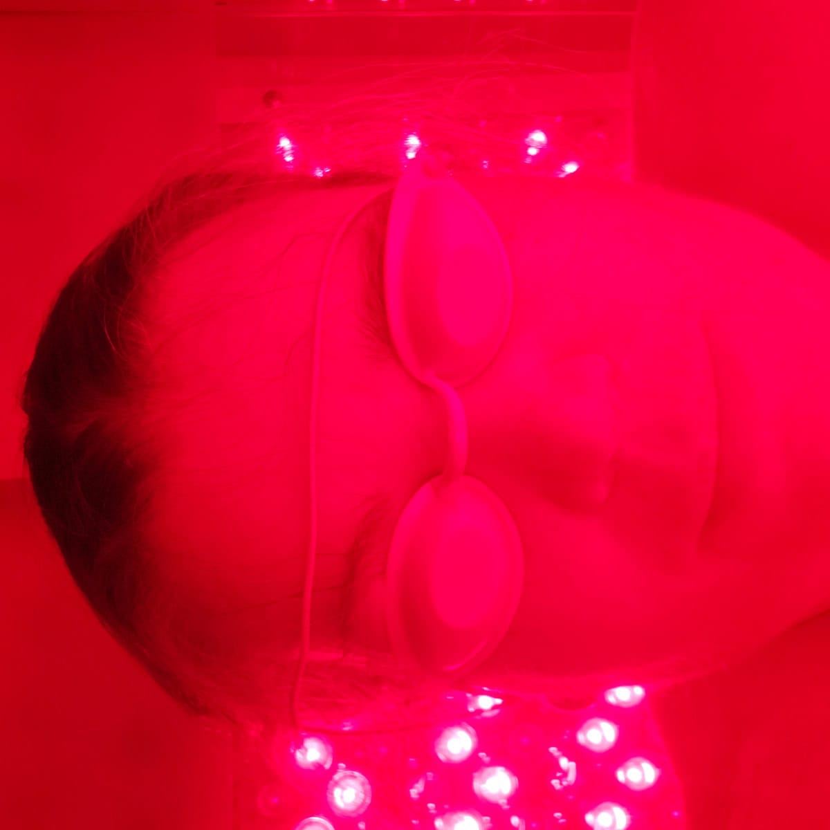 Tammilee with white glasses on with red light surrounding her