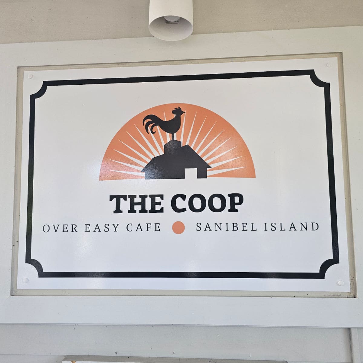 The Coop sign with Over Easy Cafe and Sanibel Island under a logo with a rooster on a barn
