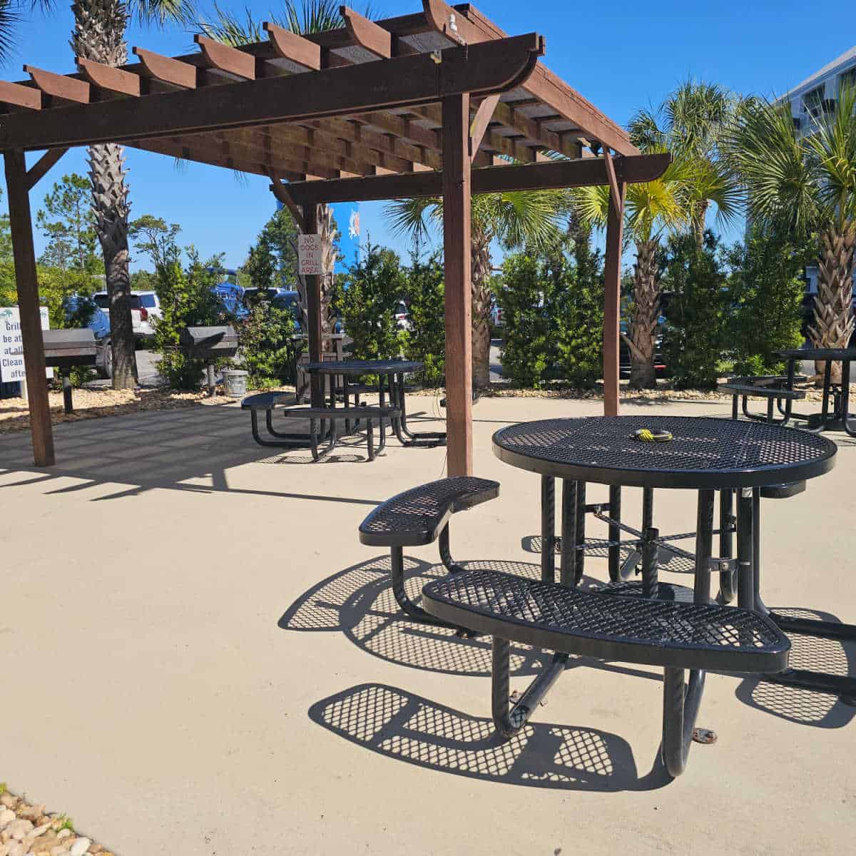 barbecue area with black metal tables and benches, pergola, and barbecues