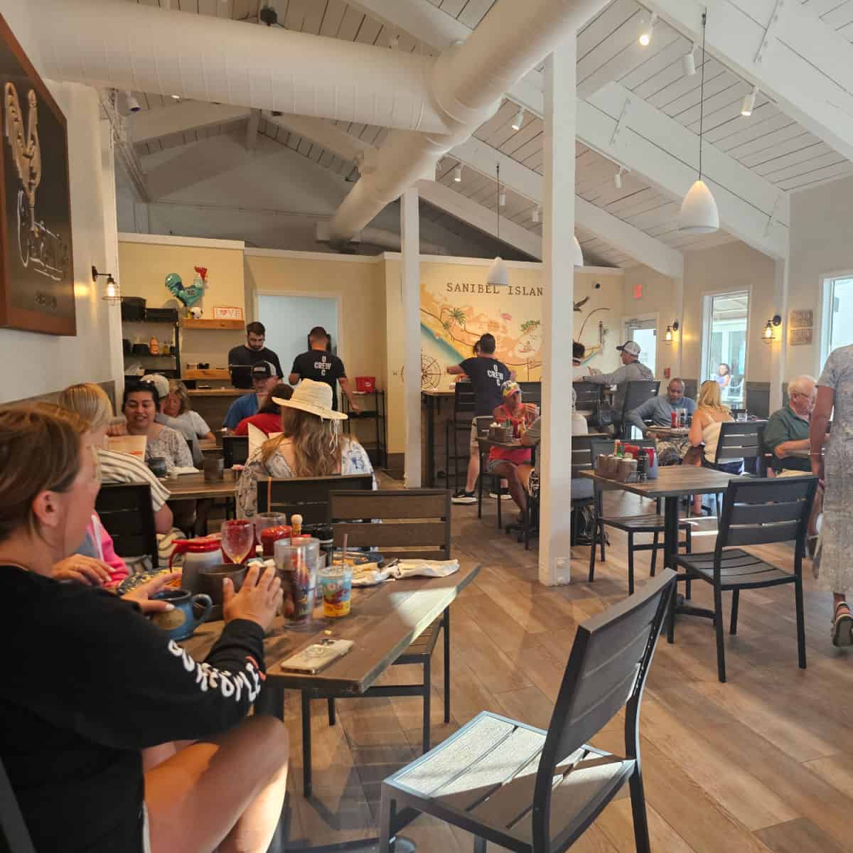 Over easy cafe indoor seating with tables and chairs, sanibel island mural on the back wall