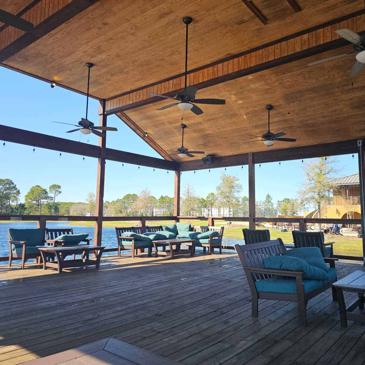 Outdoor seting with couches and tables spread around a covered rea with the lake in the background at Duplin winery