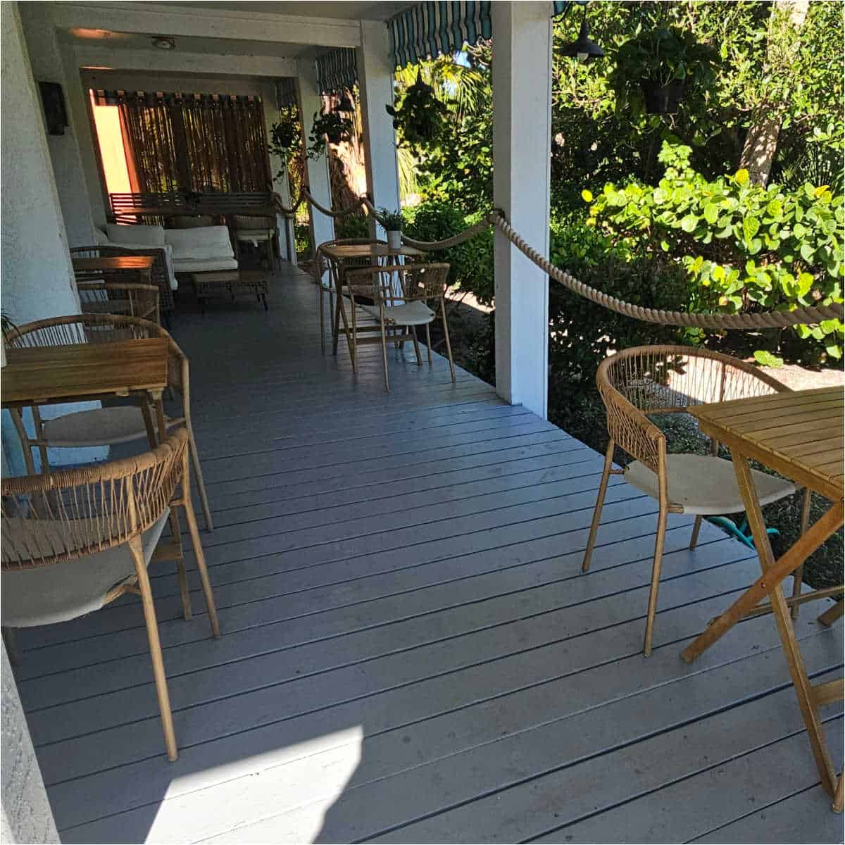 outdoor seating area at sanibel Sprout with brown chairs next to wooden tables, greenery along the outer edge of the patio