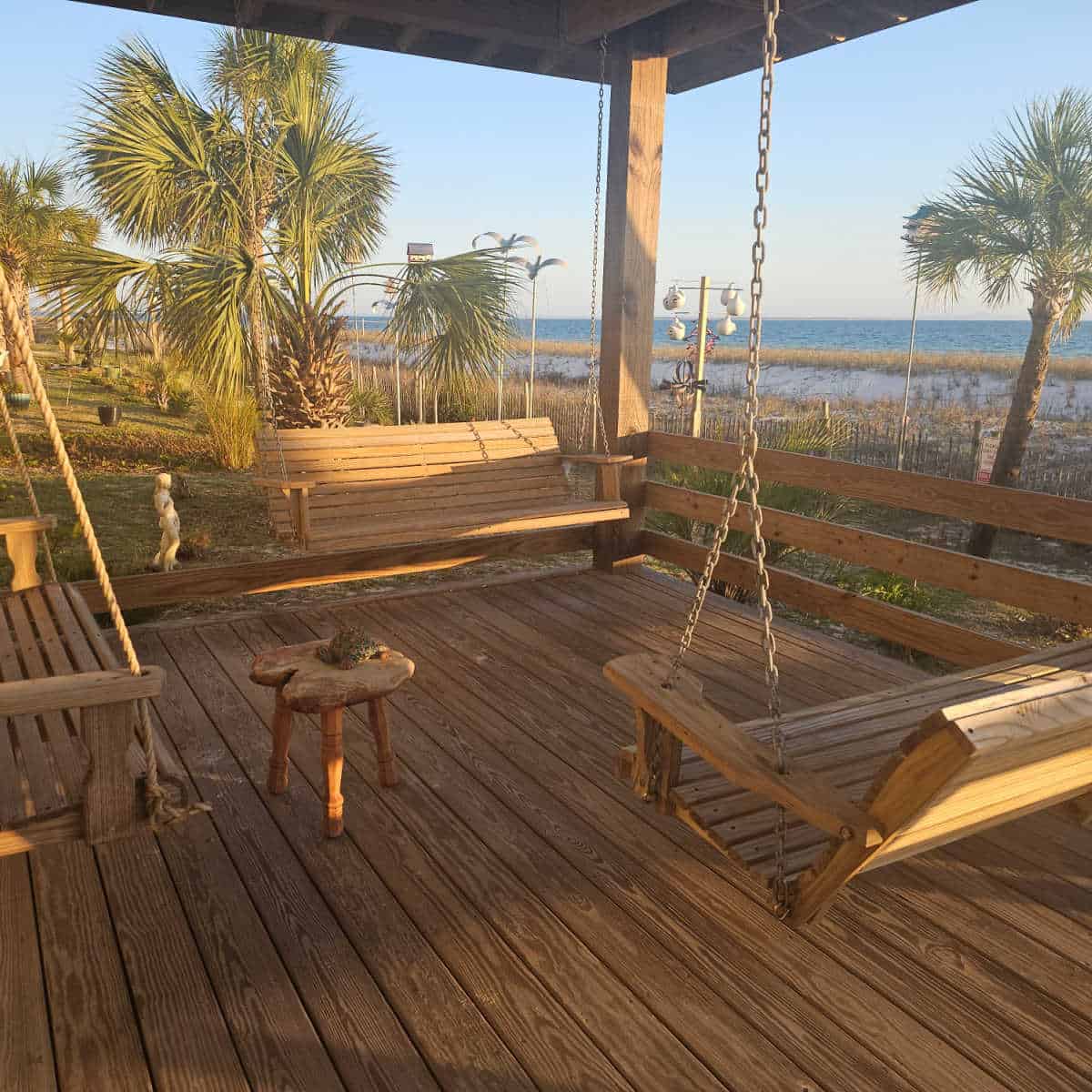hanging wooden swings under a cover with the Gulf water in the background