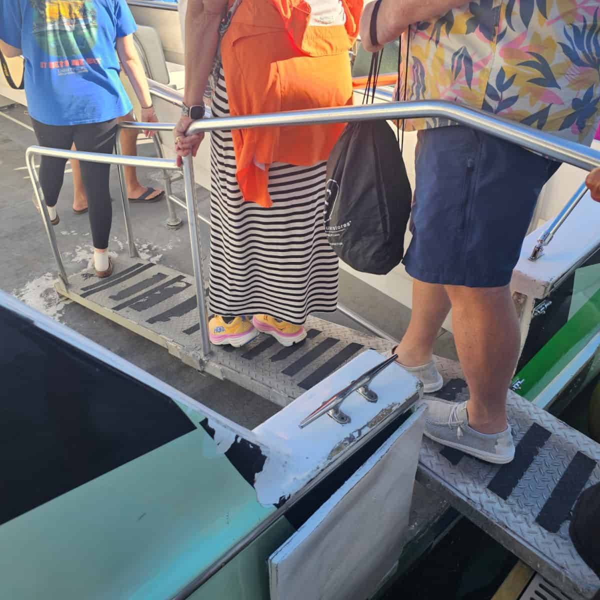 people walking on a metal gangway onto a boat