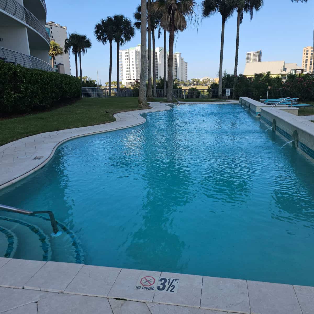 looking over a large outdoor pool with palm trees at the far end
