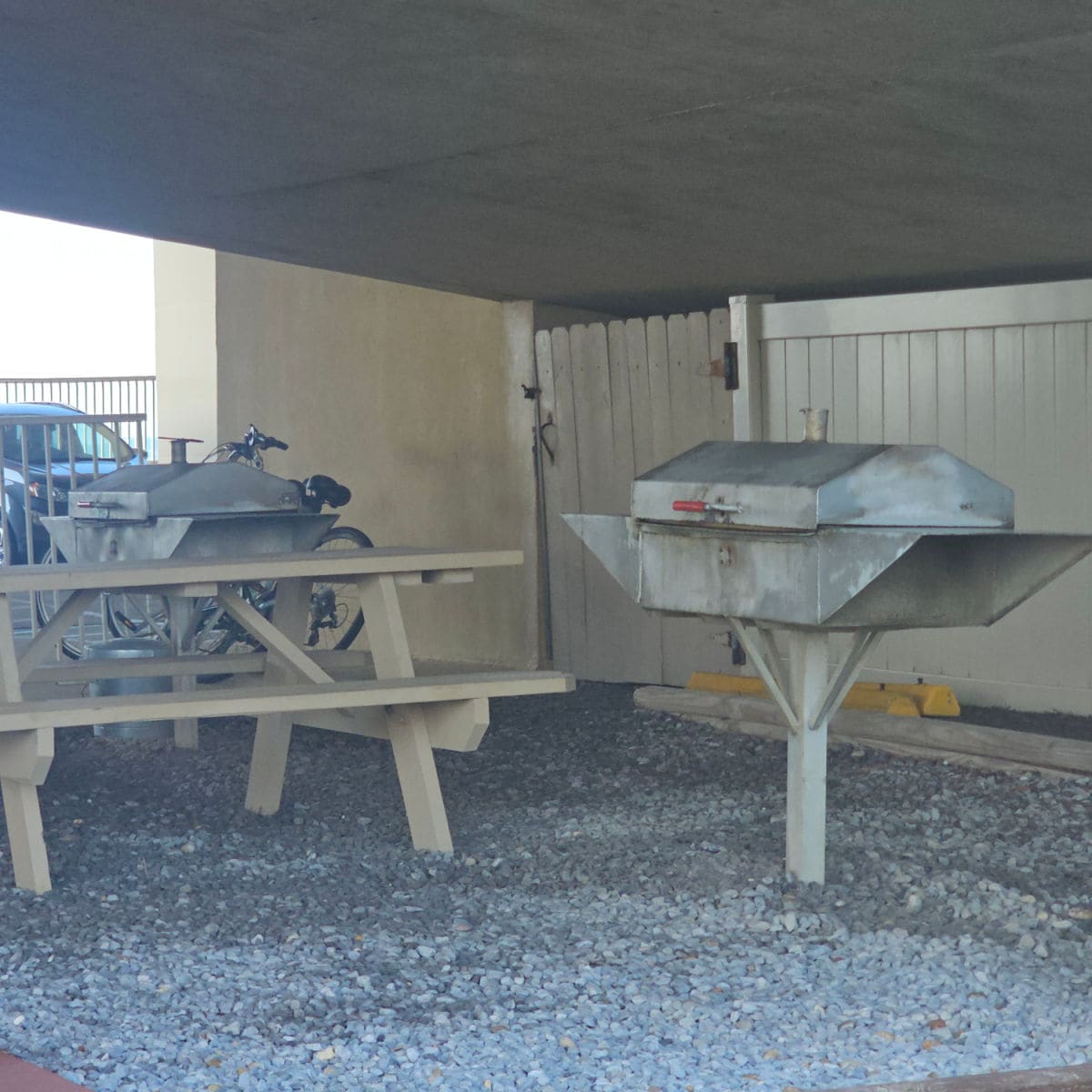 barbecues next to a picnic table under a cover