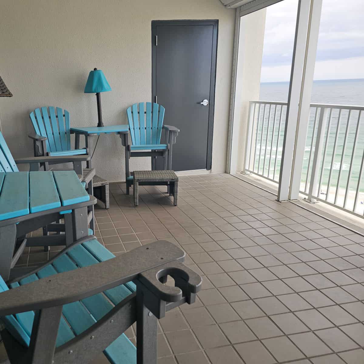 Blue and grey adirondack chairs on a balcony with the Gulf in the background.