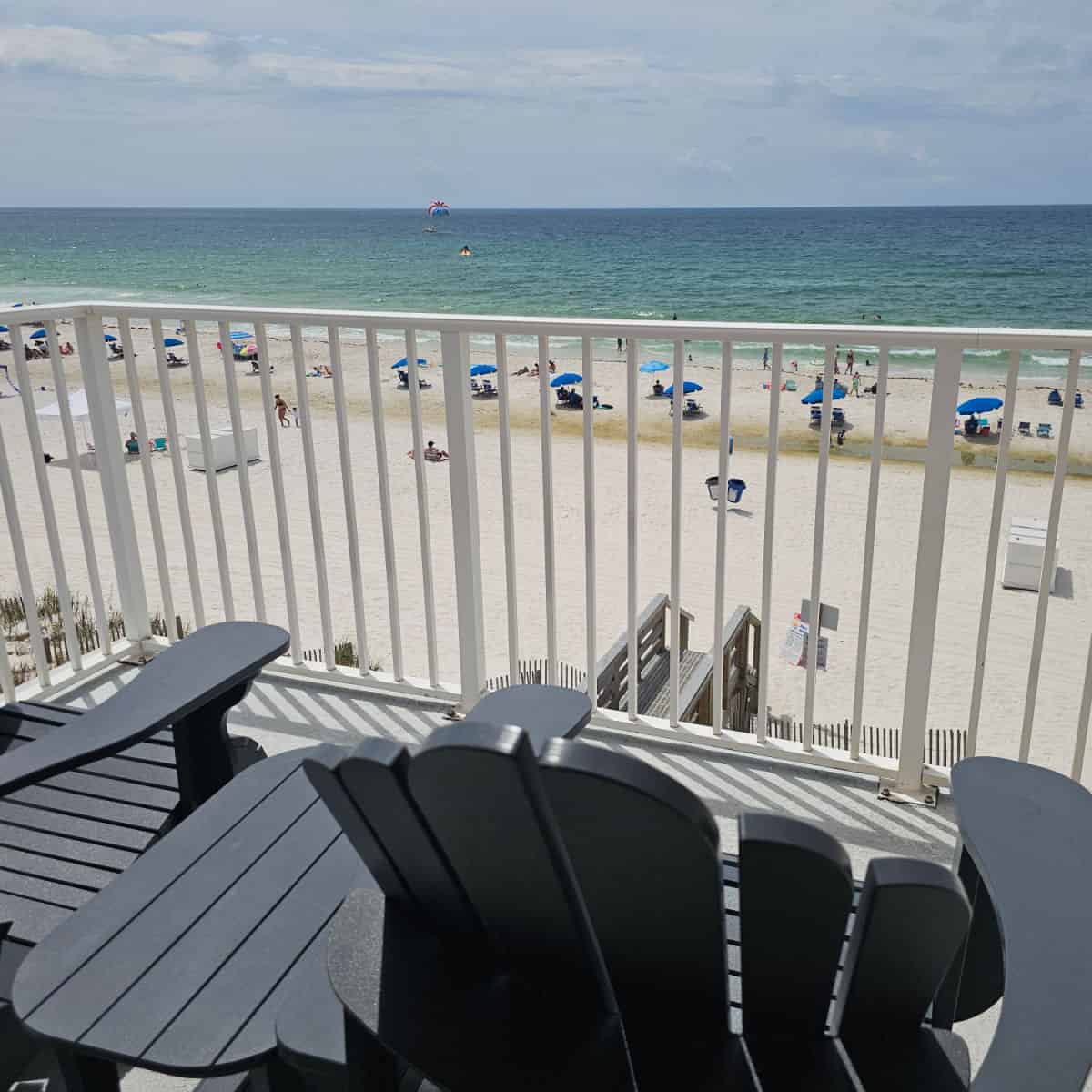 Balcony with Adirondack chairs looking out to white sand and the Gulf