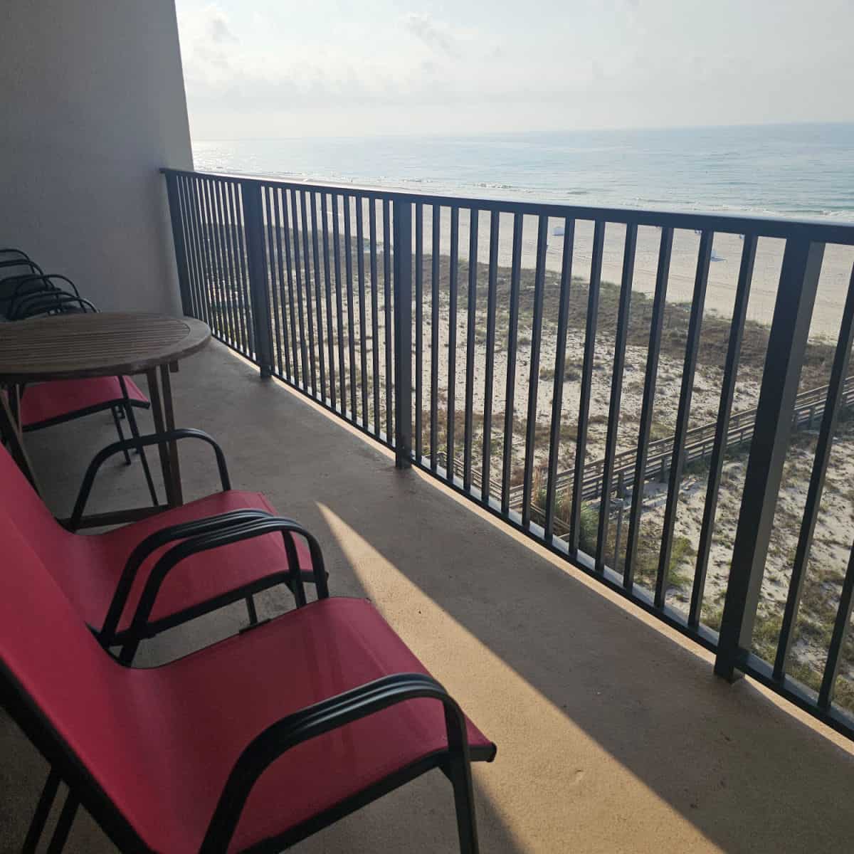 red chairs and table on a balcony overlooking the Gulf and beach