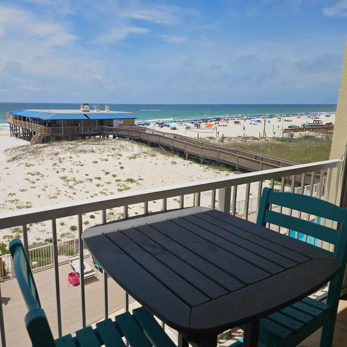 balcony with table and chair, looking out to the beach and Sea N Suds restaurant.