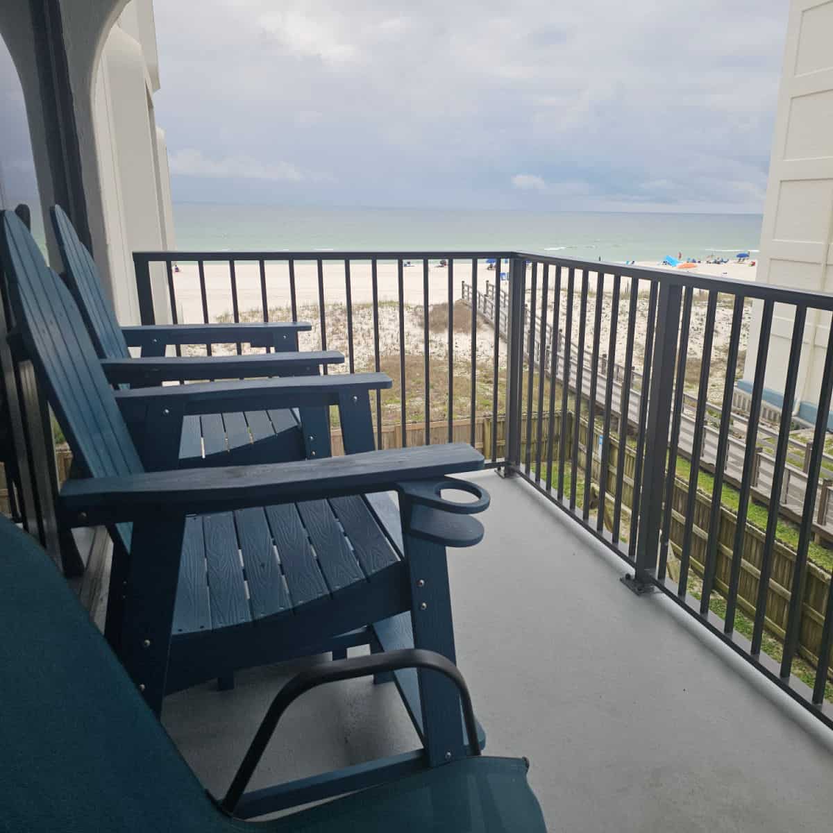 balcony with blue adirondack chairs looking out to the Gulf and beach