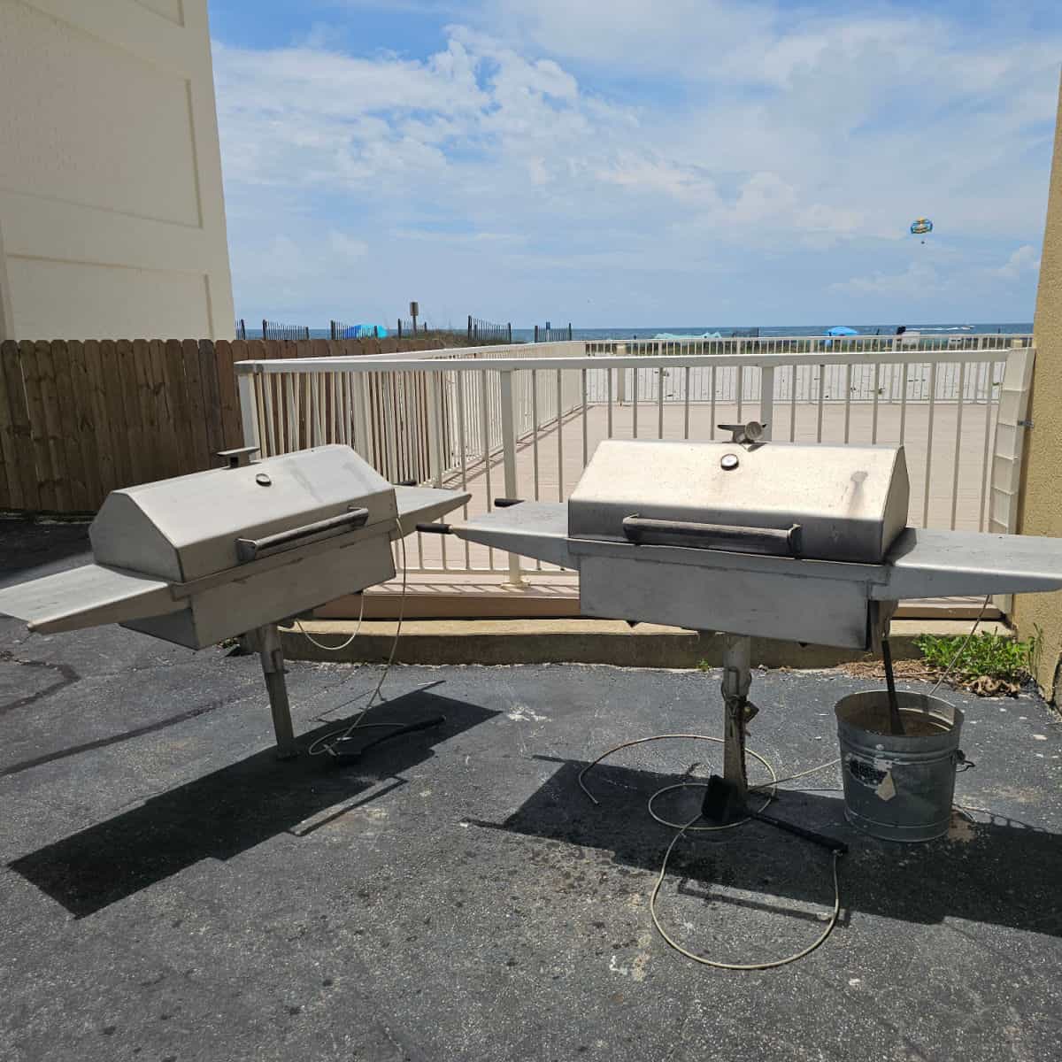 barbecue area with 2 barbecues, next to a fence