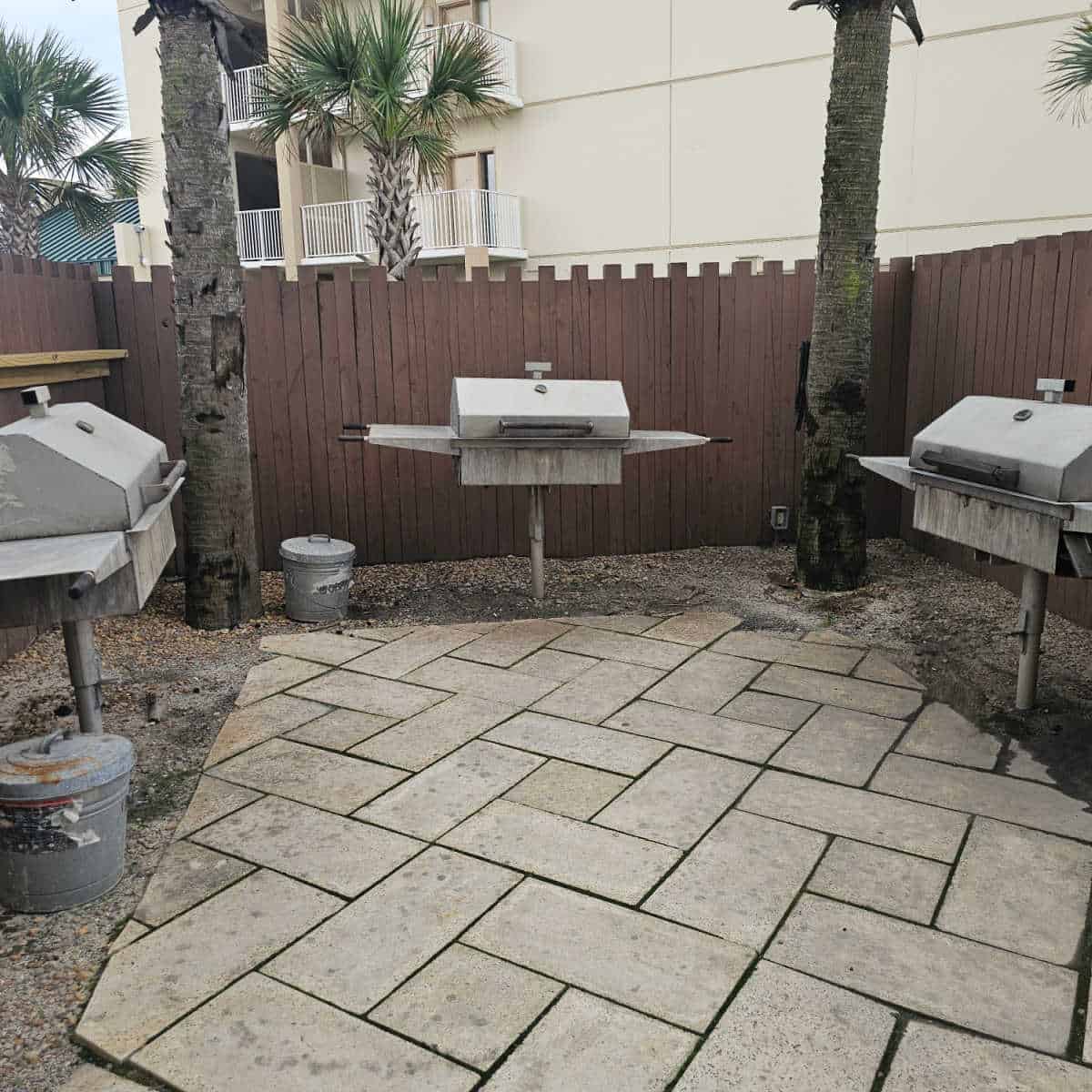 barbecue area with three charcoal barbecues, palm trees in the corner