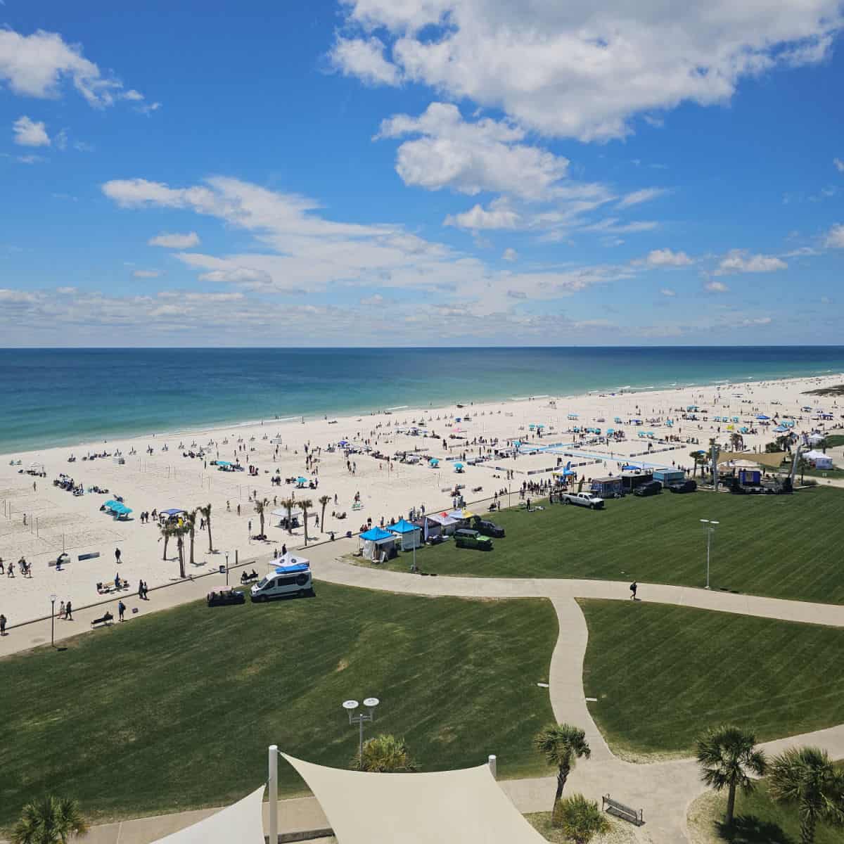 looking out to Gulf Place Beach with green space and then white sand and the Gulf of Mexico during a volleyball event