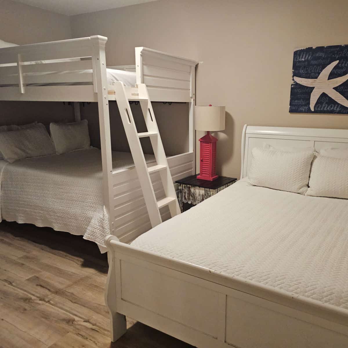 bedroom with a bunkbed and regular bed starfish art on the wall