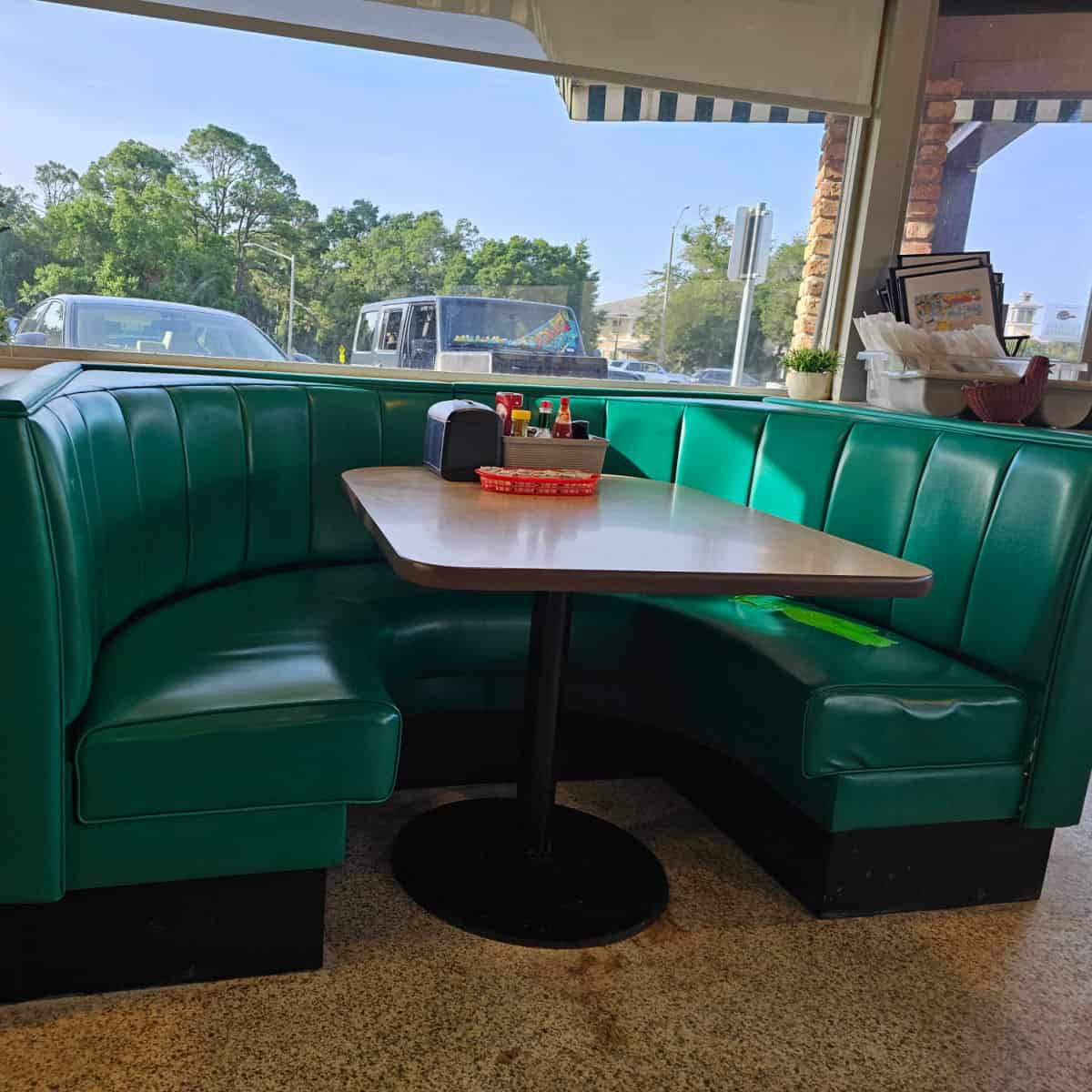 green leather covered booth with table in the middle