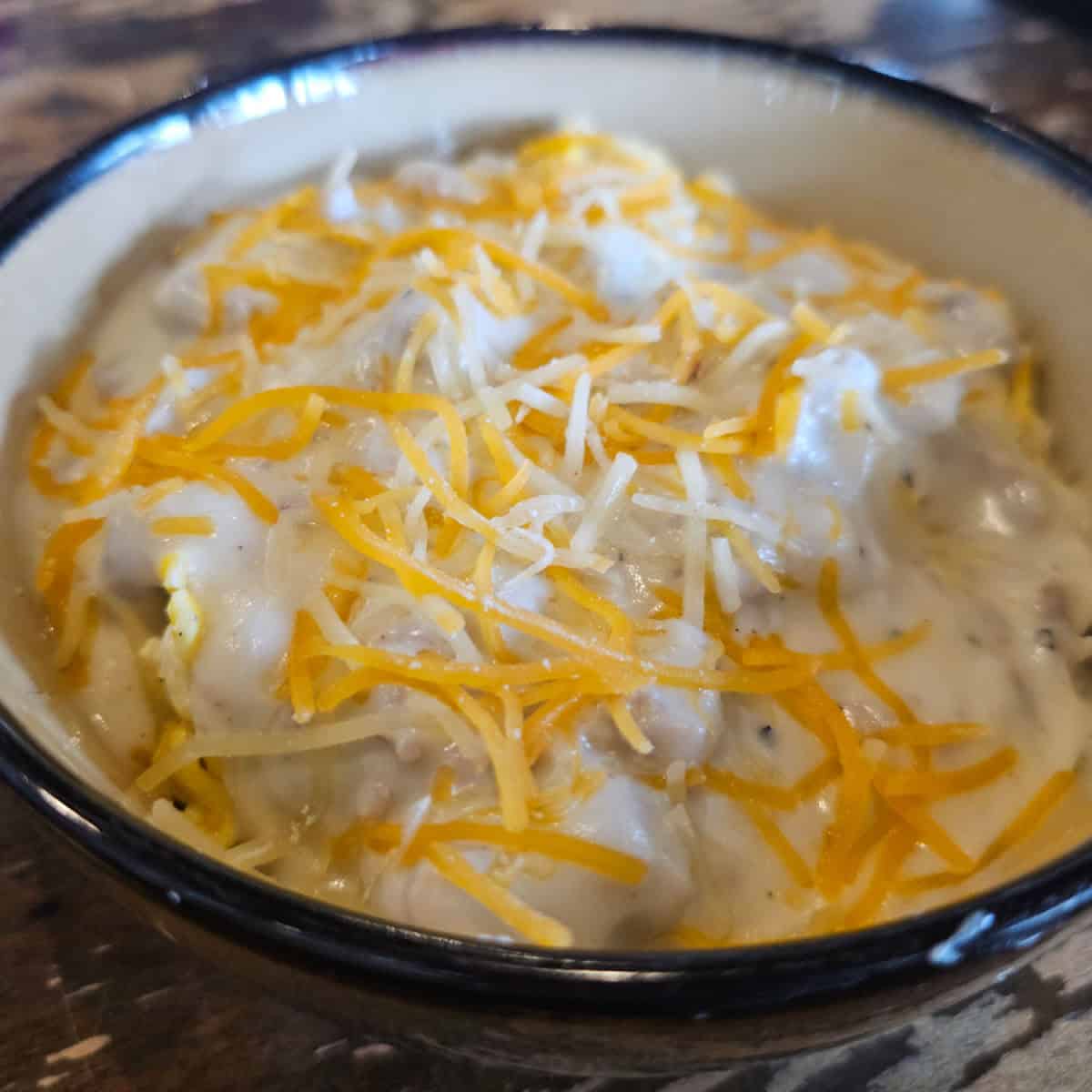 bowl with gravy covered in cheese over a biscuit