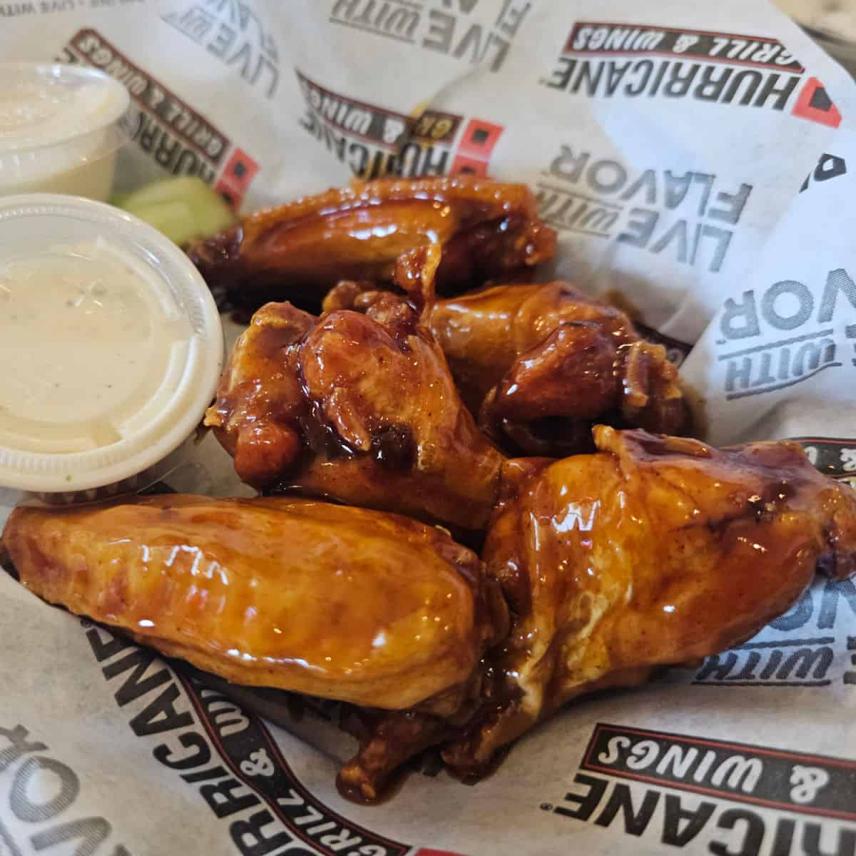wings in a Hurricane Grill & Wings paper lined basket with containers of ranch and celery