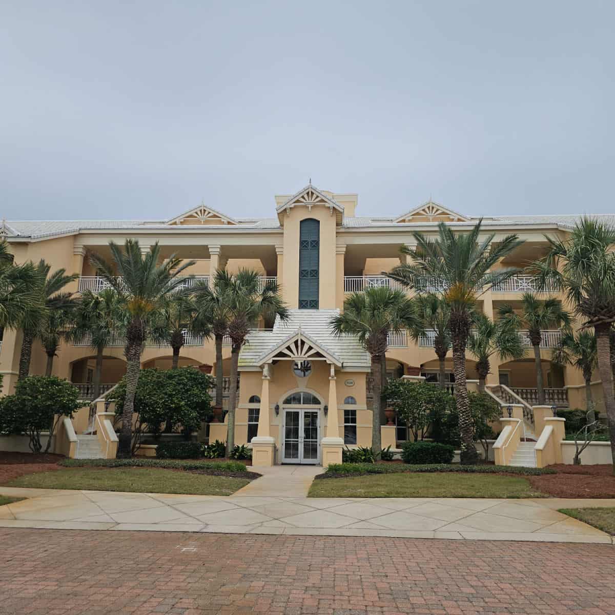yellow building with palm trees in front of it