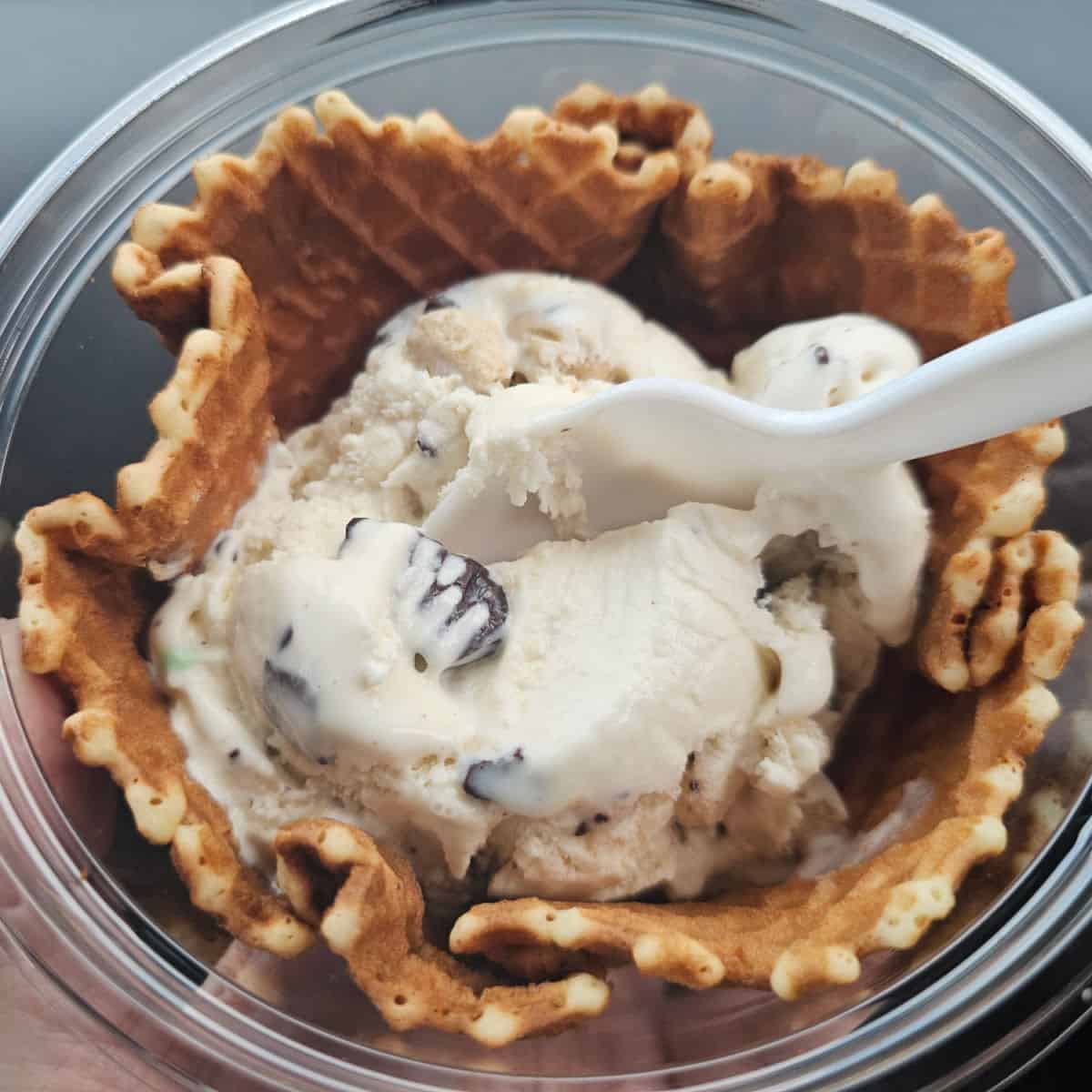 cookie dough ice cream in a waffle bowl with a plastic spoon