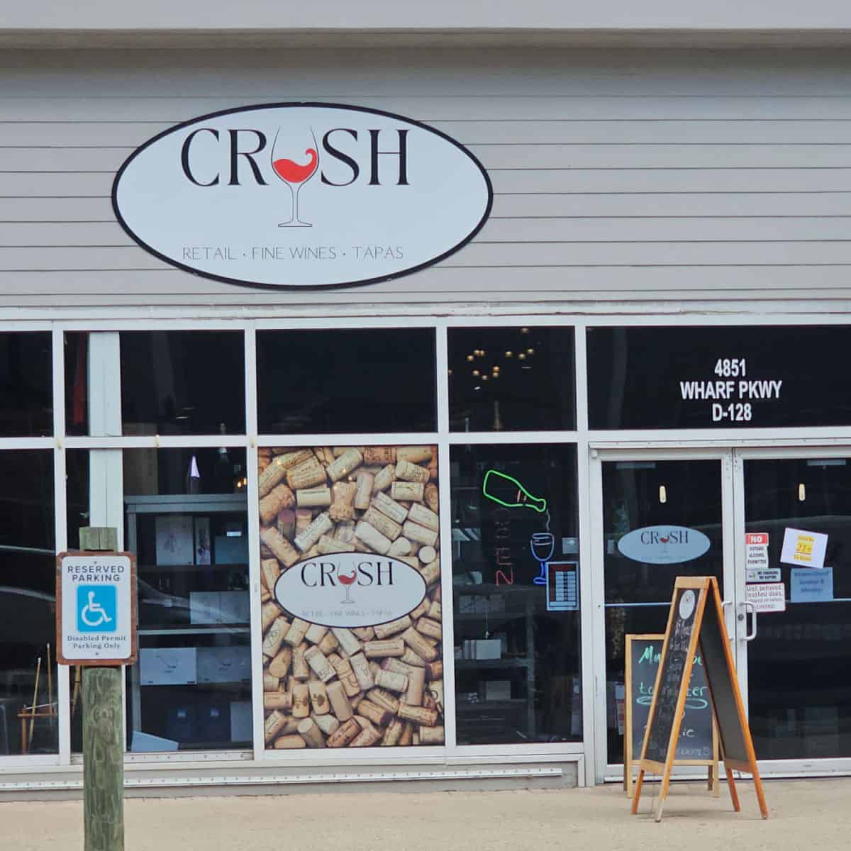 Crush sign with a wine glass, retail, fine wines, and tapas over the entrance