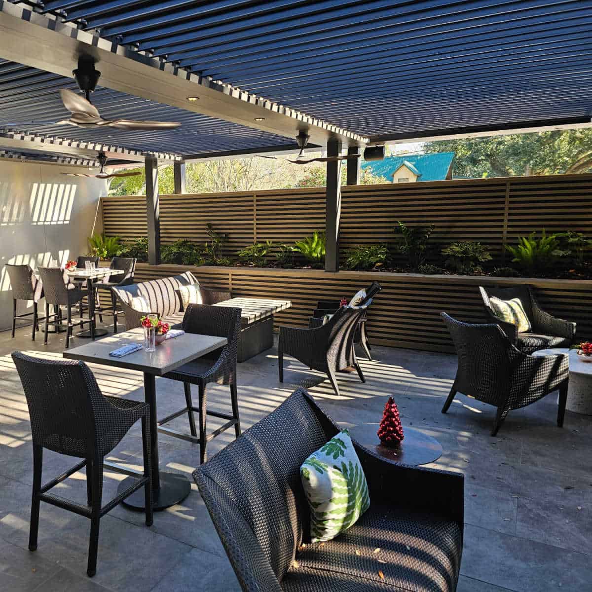 outside Daly courtyard with covered awning, tables and chairs, wall of greenery on one side