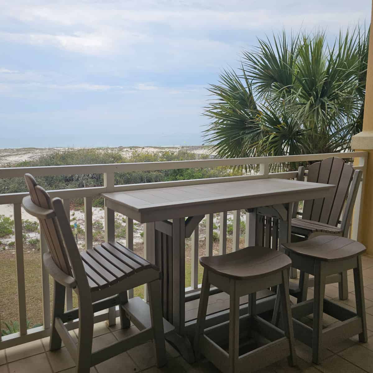 table with tall chairs and stools near the deck edge looking over sand dunes