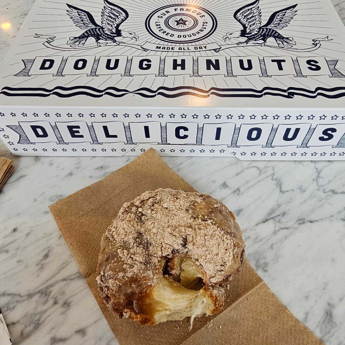 Parlor Doughnuts box next to a napkin with a donut on top of it