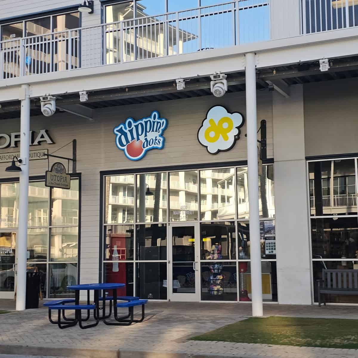 Dippin Dots sign over the glass door entrance to the restaurant with a blue table outside
