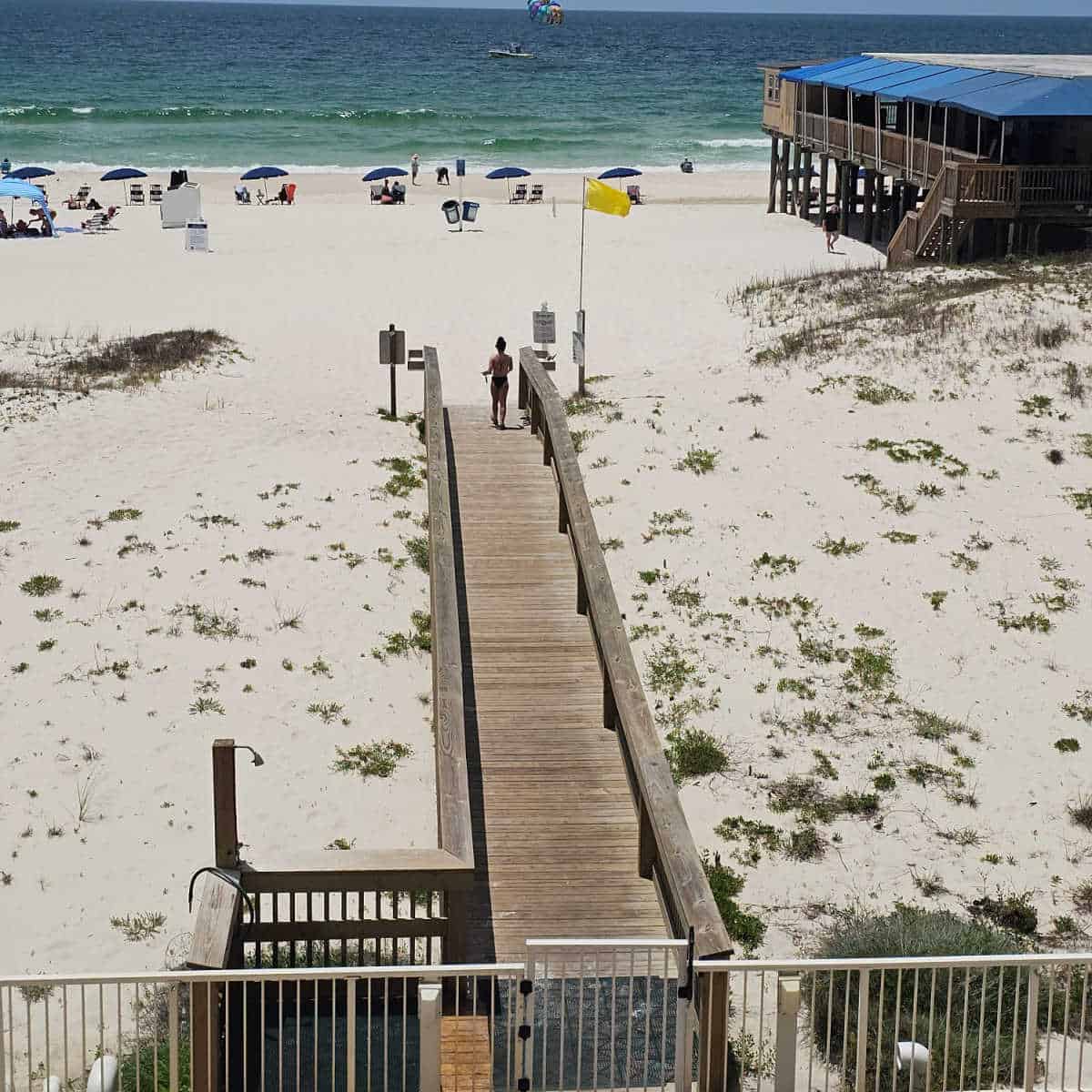 wooden boardwalk out to the beach, part of Sea n Suds restaurant restaurant in the corner.