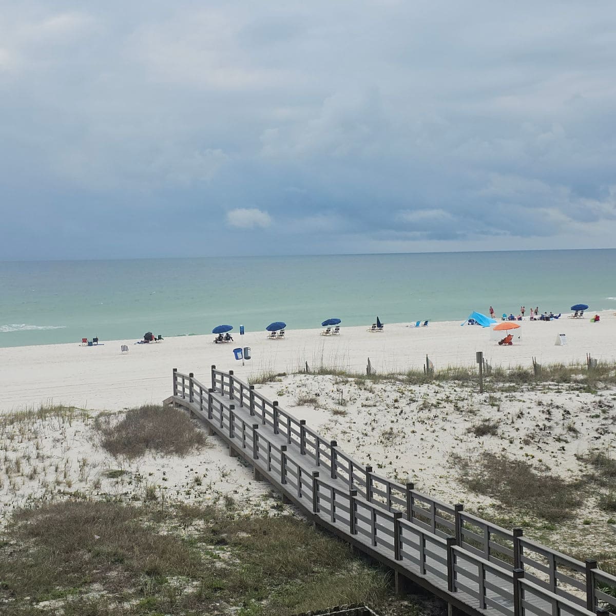 wooden boardwalk over sand dunes leading to the beach with Gulf in the background.