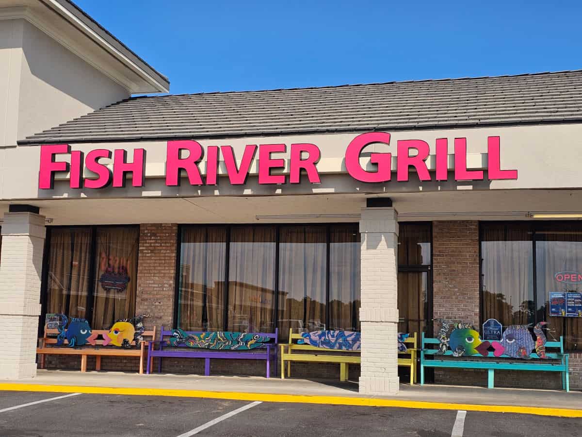 Fish River Grill sign over glass with benches in front of the restaurant