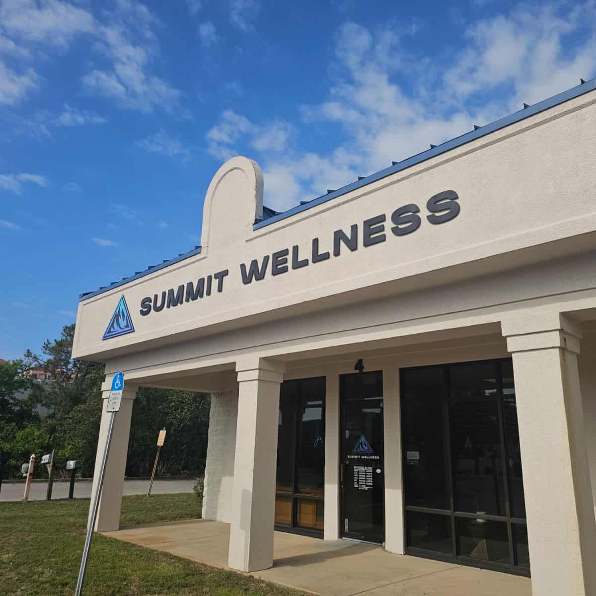 Summit Wellness sign on a white building near a glass door