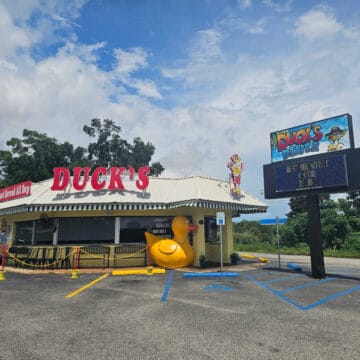 Ducks Diner restaurant with large yellow duck by the front door, Duck's diner sign with menu items on it