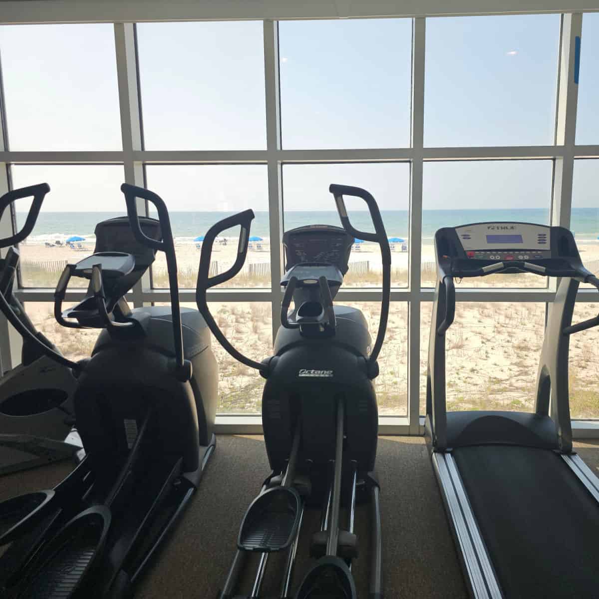 treadmill and eliptical machines near a window looking out to the beach and Gulf of Mexico