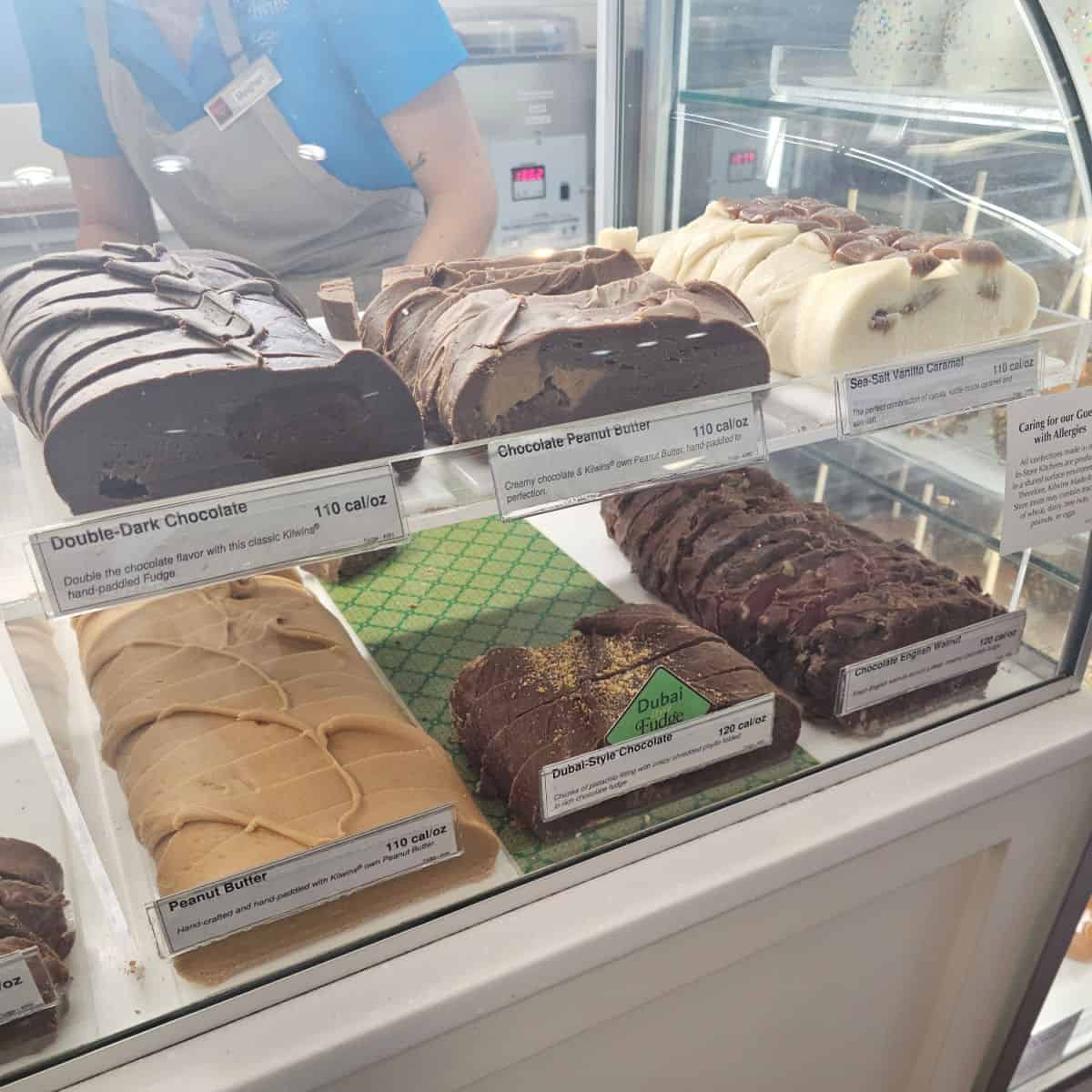 fudge slices in a case with a person behind it