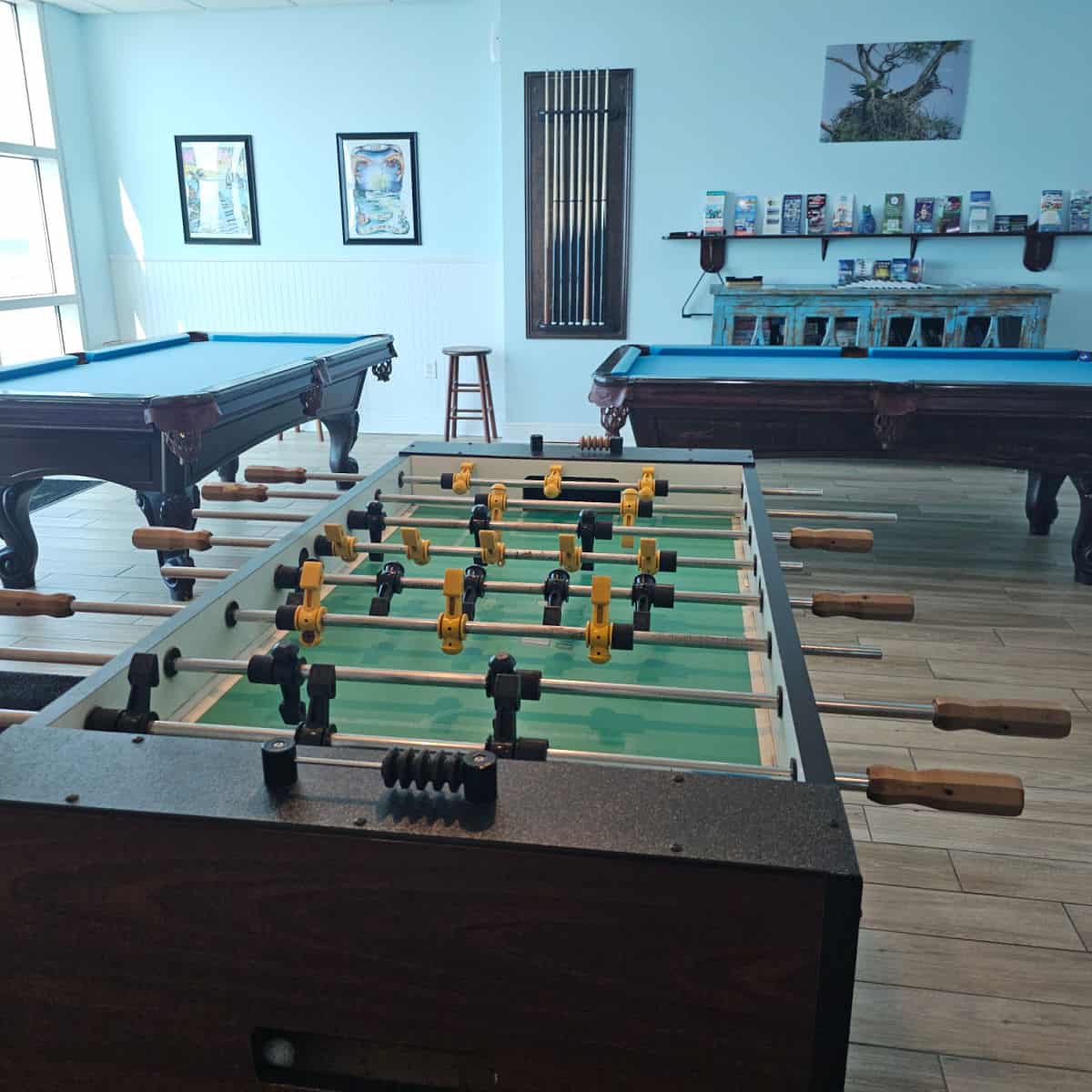 Game room with foosball and pool tables, books on shelves on the wall