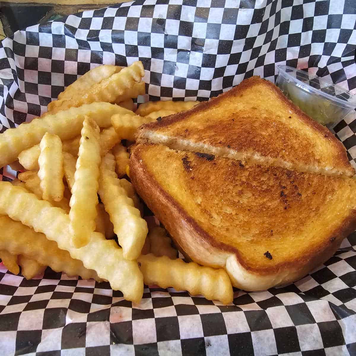 grilled cheese and fries in a black and white paper lined basket