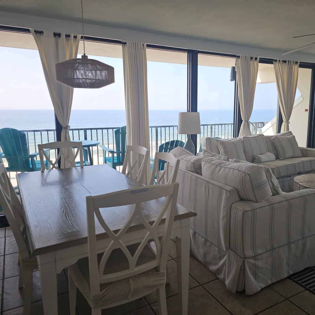 living room area with cushy couch, table and chairs, windows looking out to the Gulf
