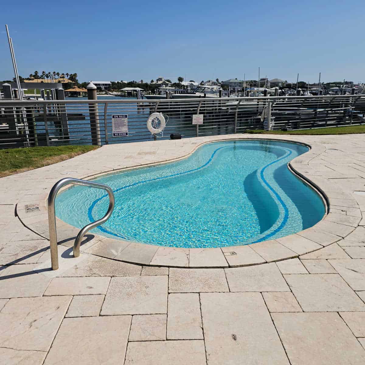 large outdoor hot tub with a silver hand rail, marina in the background